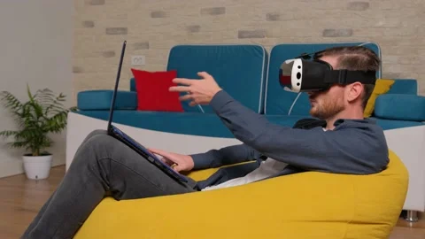 Young man wearing virtual reality headset, play at the laptop. Virtual Reality. Stock Footage 141366022