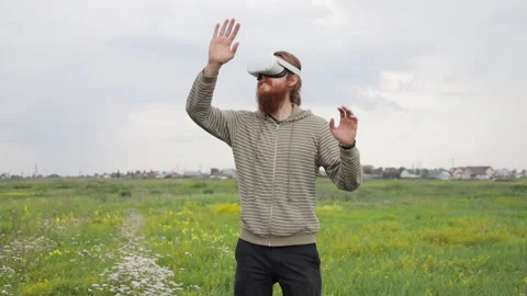Young Man Wearing Virtual Reality Glasses in Field Looking Around and Using Web Stock Footage 212662695