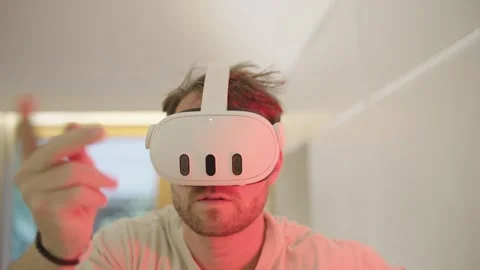 Young man wearing vr headset exploring an interactive futuristic world lit by Stock Footage 335204289
