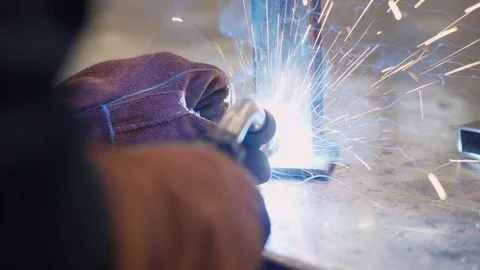 Young man welds two pieces of metal together Stock Footage 103337908