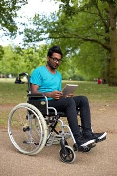 Young man in a wheelchair using a tablet computer Stock Photos