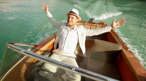 Young man in white clothes sitting in boat riding on lake. raising hands Stock Footage 42947521