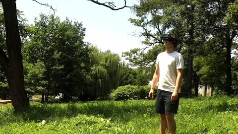 Young man white clothes using VR glasses outdoor with sunny green nature on ba 스톡 동영상 116795948