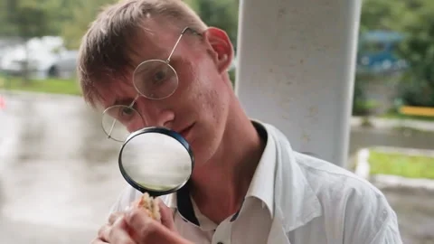 Young Man in White Coat Observing Object Through Magnifying Glass Stock Footage 321128474