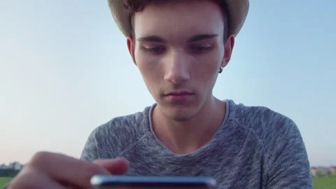 Young man in white hat holding mobile phone in front of him, camera tracking Stock Footage 304975237