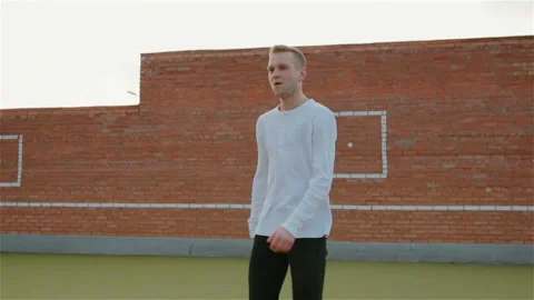 A young man in a white jacket and black pants effectively dancing the bottom Video stock 106660848