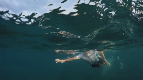 young man in a white shirt is swimming o... | Stock Video | Pond5