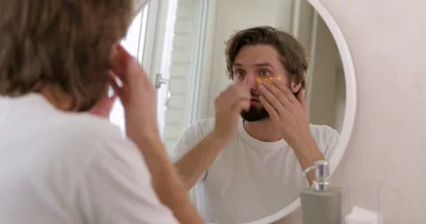 Young man in white shirt using korean golden patches under eyes for preventing Stock Footage 142529753
