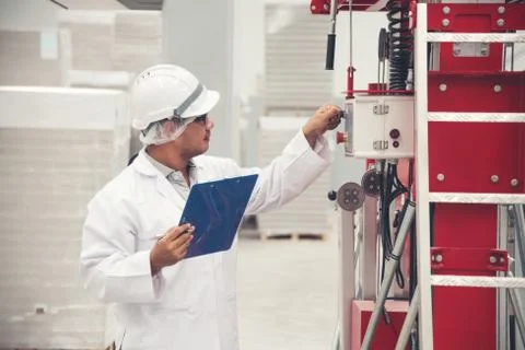 Young man white uniform checking machine equipment at store factory Stock Photos