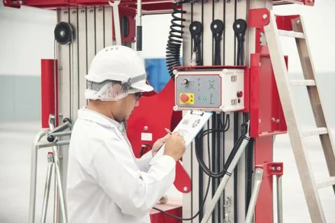 Young man white uniform checking machine equipment at store factory Stock Photos