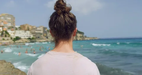 Young Man at Windy Beach Seaside in Sunshine. Long Bun Hair Hipster Traveller Stock Footage 94426370