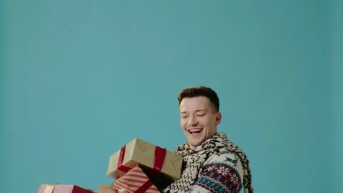 A young man in winter clothes on a blue background throws gift boxes. Stock-Footage 226219165