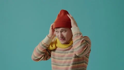 A young man in winter clothes on a blue background blows on hands, feels cold. Stock-Footage 226220083