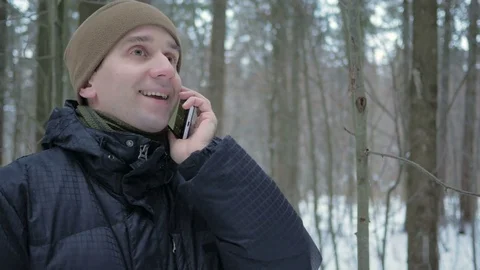 A young man in winter forest talking on the phone. He admires the sides of snow Stock Footage 71211916