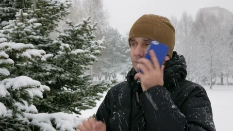 A young man in winter forest talking on the phone. Big snowfall. He admires the Stock Footage 71215449