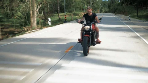 Young man without helmet riding his orange motorcycle, stabilized shot Vídeo Stock 90280870