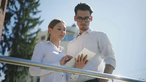 Young man woman using tablet computer standing public space talking laptop Stock Footage