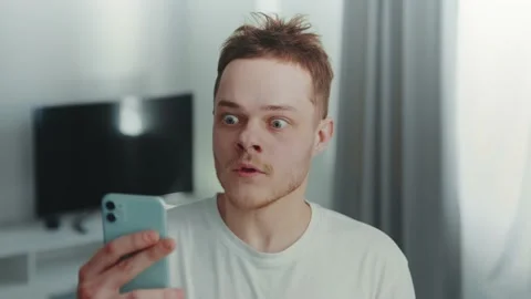 Young man wondering while looking on smartphone 스톡 동영상 172582377
