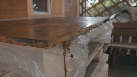 Young man in work uniform and gloves covers the wooden tabletop 库存影片 145260754