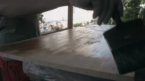 Young man in work uniform and gloves covers the wooden tabletop Vidéo 145260821