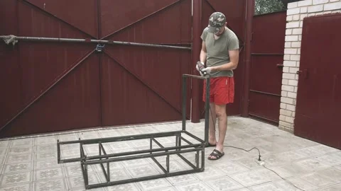 A young man in a work uniform and gloves wipes a metal frame with a degreaser Vidéo 145395179