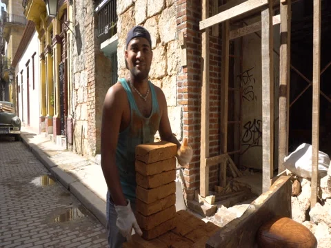 Young man worker puts bricks on the construction at summer sunny day Stock Footage 71056923