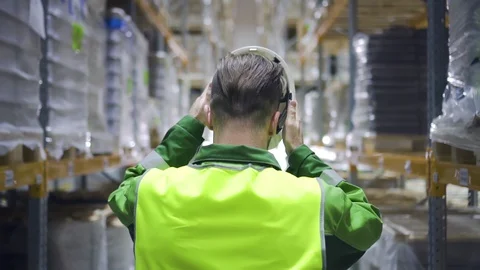 Young man worker putting helmet on head while walking in industrial warehouse. Stock Footage 127673742