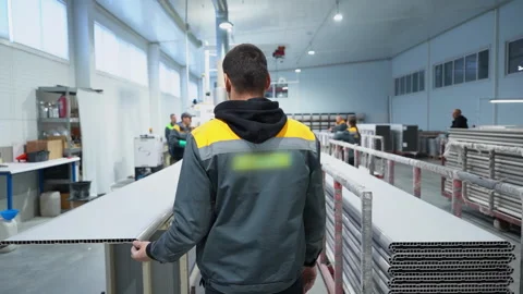 Young man worker in uniform stands near stacked plastic profile 스톡 동영상 304428608