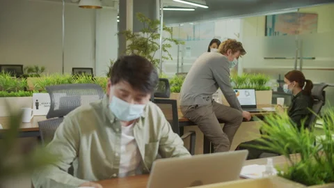 A young man is working and his colleagues are discussing on a project Stock Footage 160176559