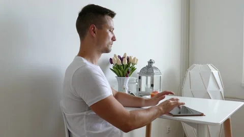 Young man working and touching lying tablet on the table in the kitchen Stock Footage 135809341
