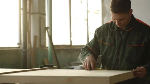 Young man working as carpenter and measuring board Stock Footage 76277814