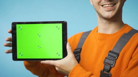 Young man in working clothes holding a tablet with green screen and smiling Stock Footage 144252898
