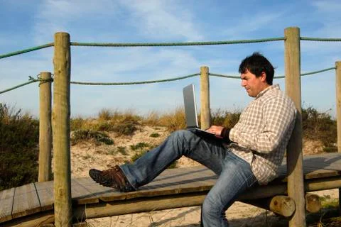 Young man working with computer at the beach Stock Photos
