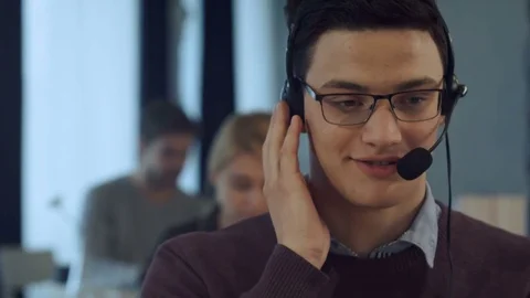 Young man working at a computer in a call centre smiling Vídeos de archivo 78723789