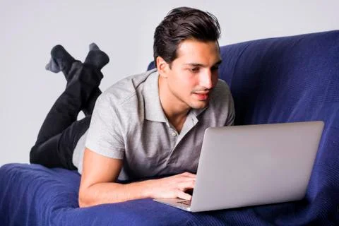 Young man working with computer on couch Stock Photos