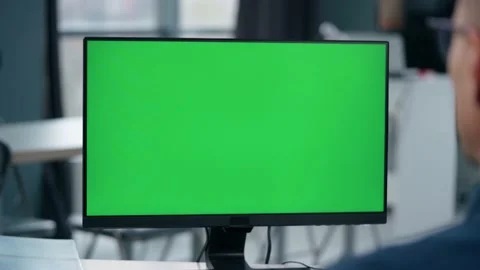 Young Man Working At Computer With Green Mock Up Screen in Office. Close Up  Stock Footage 238773200