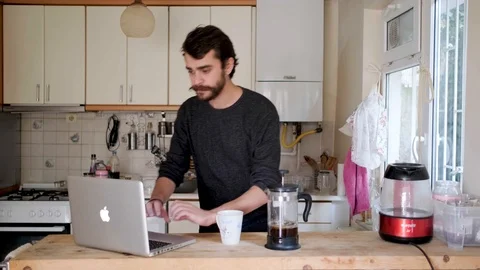 Young Man Working With A Computer In The Kitchen Drinking Coffee And Smiling Stock Footage 119218030