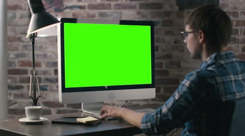 Young man is working on a computer with a mock-up green screen Stock Footage 57231117