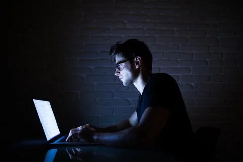 Young man working on computer at night in dark office. The designer works in  Foto stock