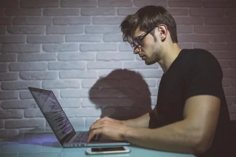 Young man working on computer at night in dark office. The designer works in  Foto stock