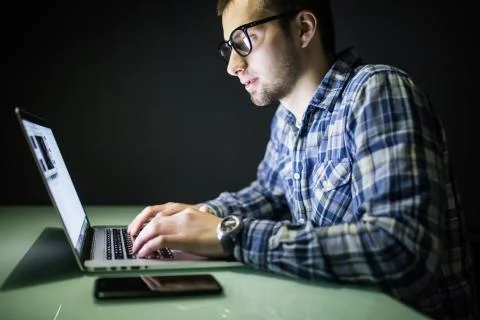 Young man working on computer at night in dark office. The designer works in  스톡 사진