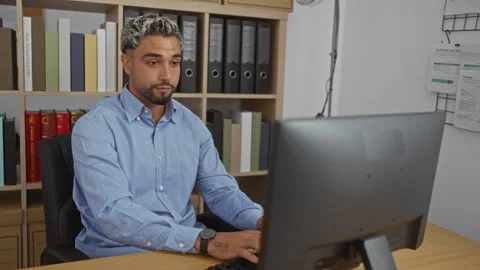 Young man working on a computer in an office environment with shelves and f.. Stock Footage 288443682