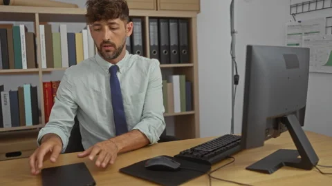 Young man working on computer in office with shelves and folders in the bac.. Stock Footage 292128073