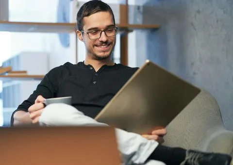 Young man working with computer, phone and tablet at the table while drinking Stock Photos