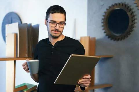 Young man working with computer, phone and tablet at the table while drinking Stock Photos