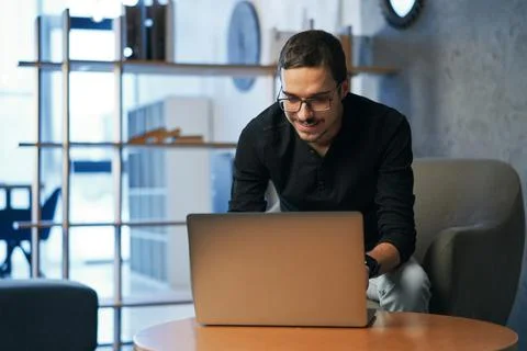Young man working with computer, phone and tablet at the table while drinking Stock Photos