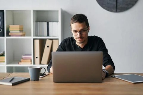 Young man working with computer, phone and tablet at the table while drinking Foto stock