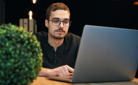 Young man working with computer, phone and tablet at the table while drinking Stock Photos