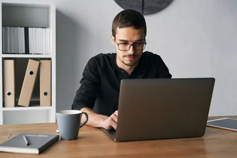 Young man working with computer, phone and tablet at the table while drinking Stock Photos