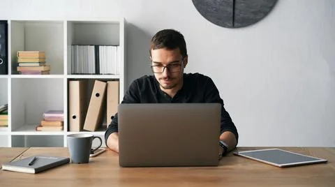 Young man working with computer, phone and tablet at the table while drinking Stock Photos
